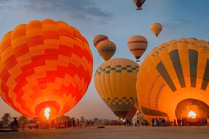 Hot air balloons inflating at dawn in Luxor, Egypt, pre-flight briefing for sunrise ride with hotel transfer