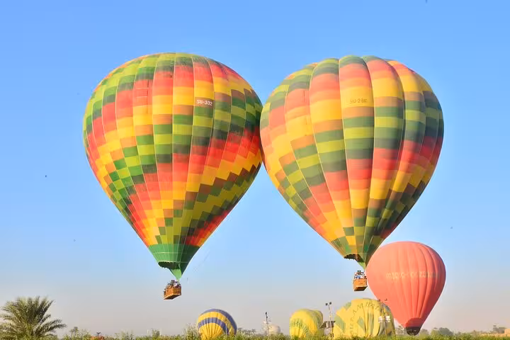 Colorful hot air balloons soar over Luxor West Bank at sunrise, offering breathtaking aerial views of ancient landscapes.