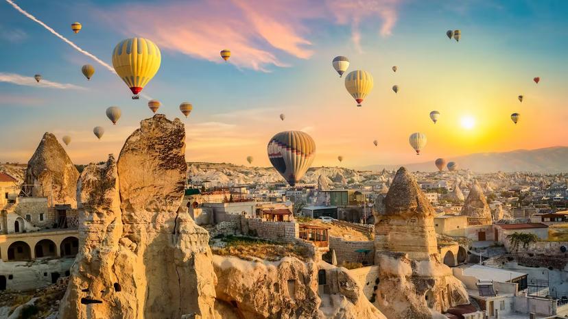 Hot air balloons at sunrise above Cappadocia’s fairy chimneys and town