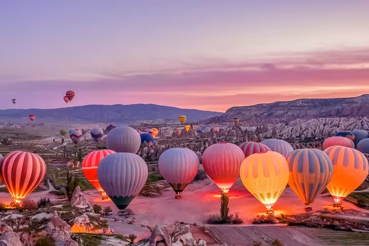 Colorful hot air balloons inflating at dawn in Cappadocia on a 2-day tour from Istanbul, Turkey