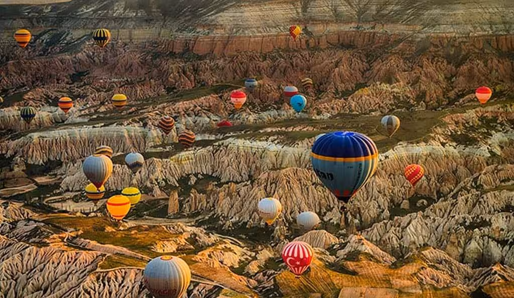 Hot air balloons floating over Cappadocia valley landscape