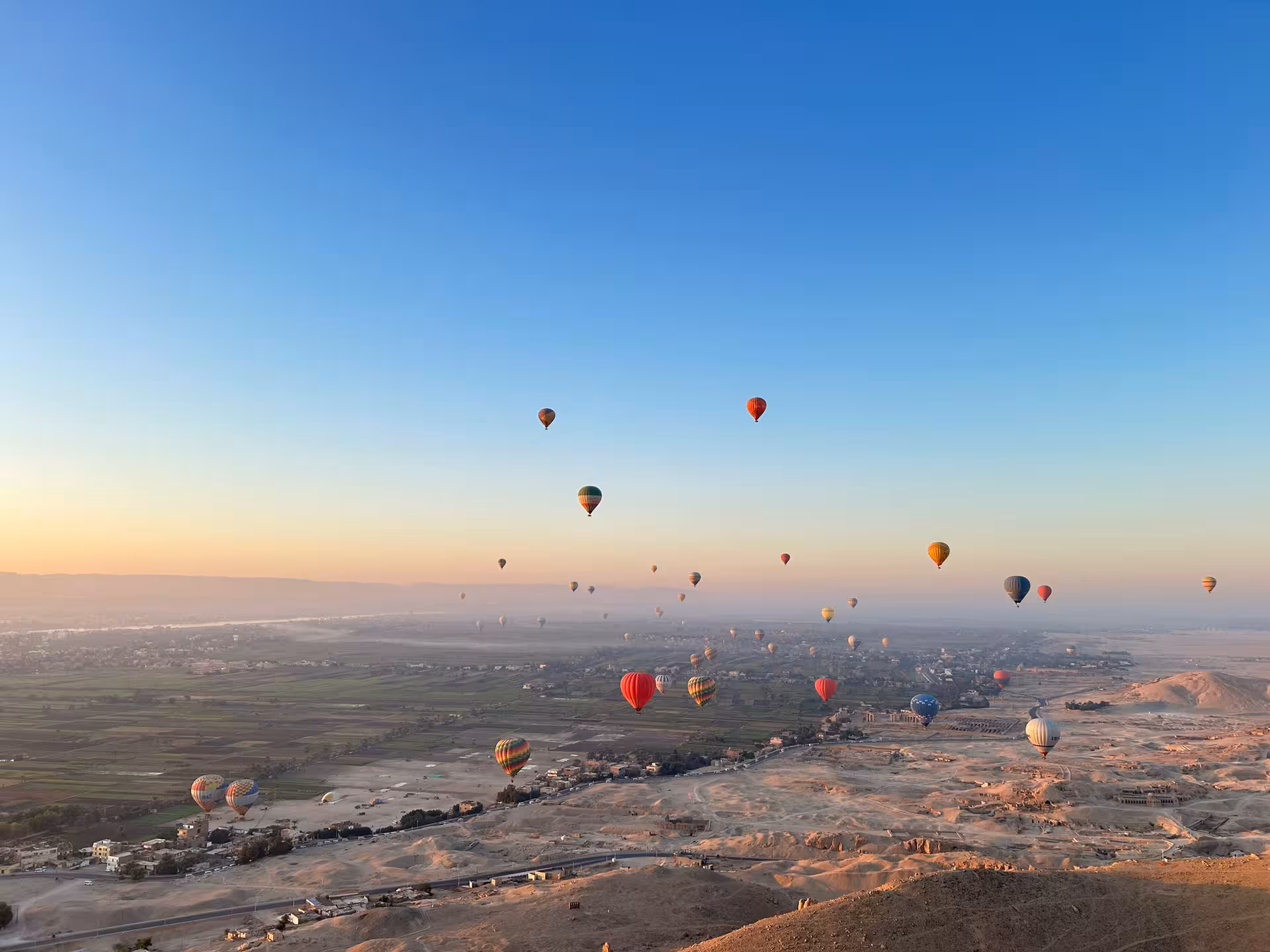 Hot air balloons soaring over the scenic Nile Valley landscape at sunrise during a 13-day Cairo and Red Sea adventure.