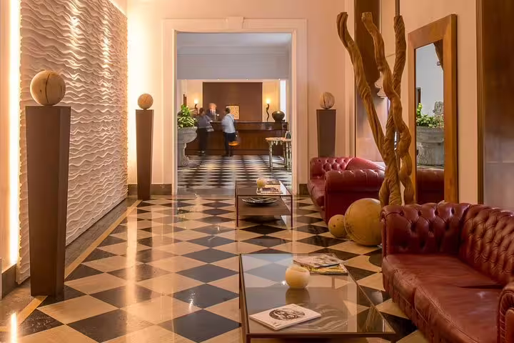 Elegant lobby of Hotel Federico II Central Palace in Palermo with leather sofas, art décor and checkered marble floor