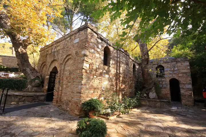 Visit the serene House of the Virgin Mary near Ephesus, surrounded by lush greenery and historical stone walls.