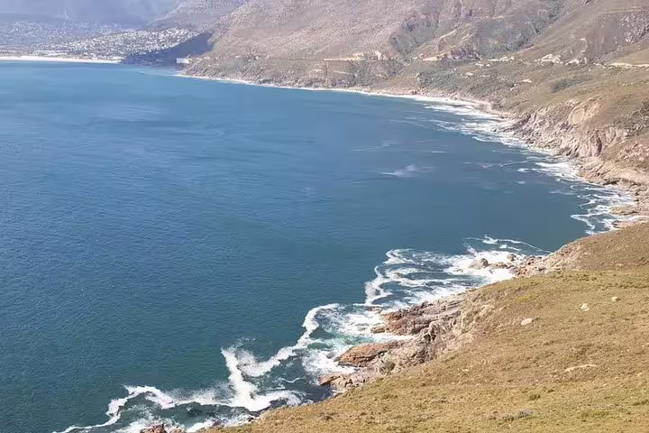 Scenic coastal view of Hout Bay with rocky shoreline and expansive blue waters.