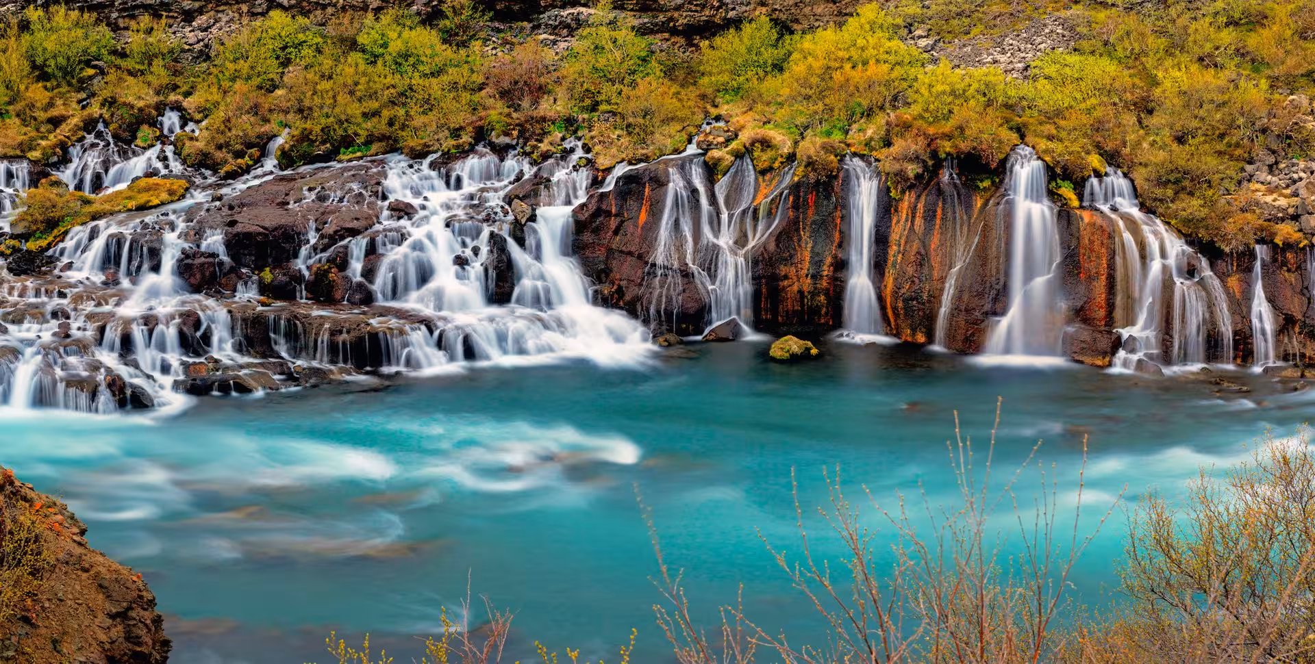 Stunning Hraunfossar waterfalls cascade over volcanic rocks into turquoise river, ideal for Iceland self-drive exploration.