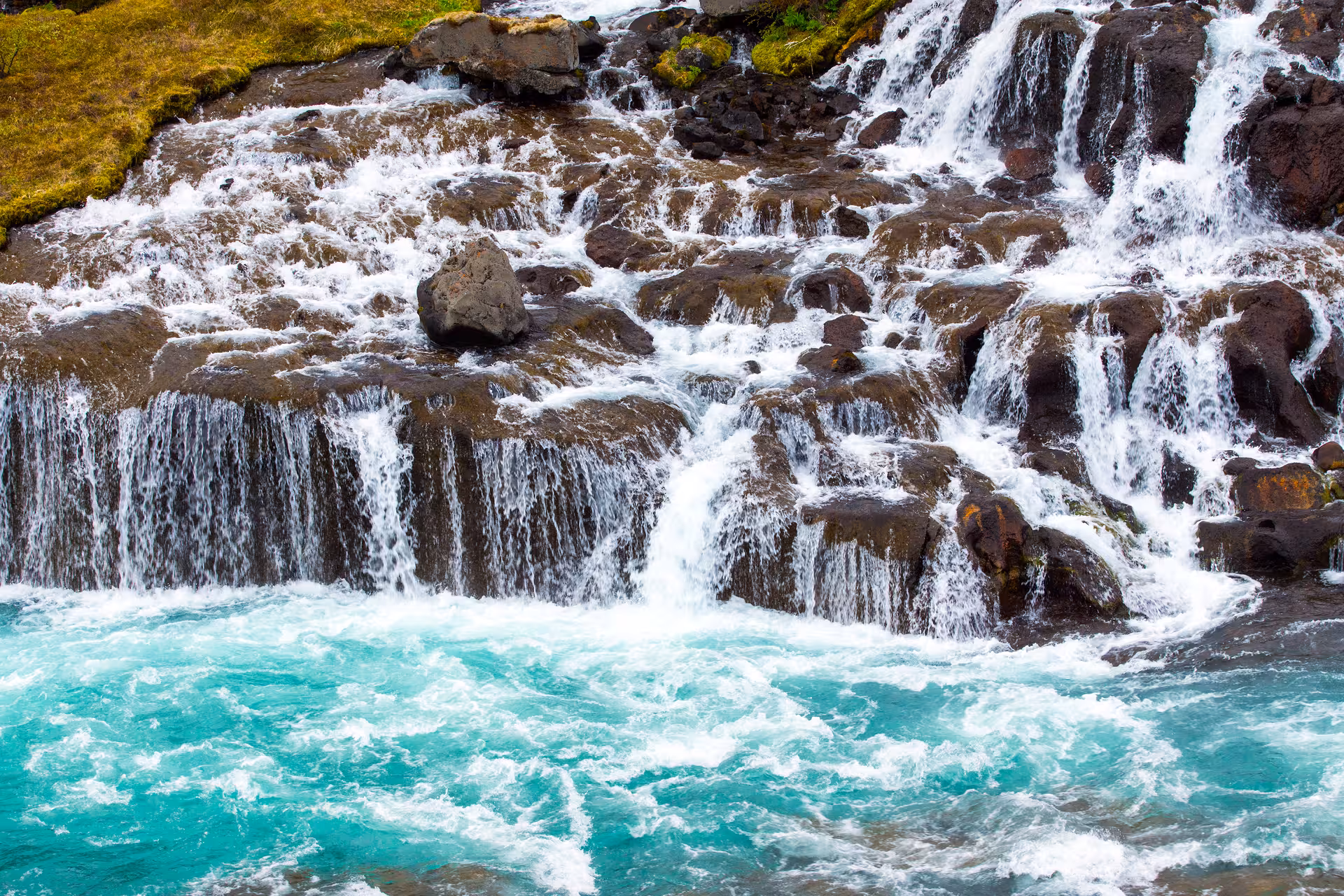 Close-up of cascading Hraunfossar waterfall with turquoise waters and rocky terrain on the Silver Circle Private Tour.