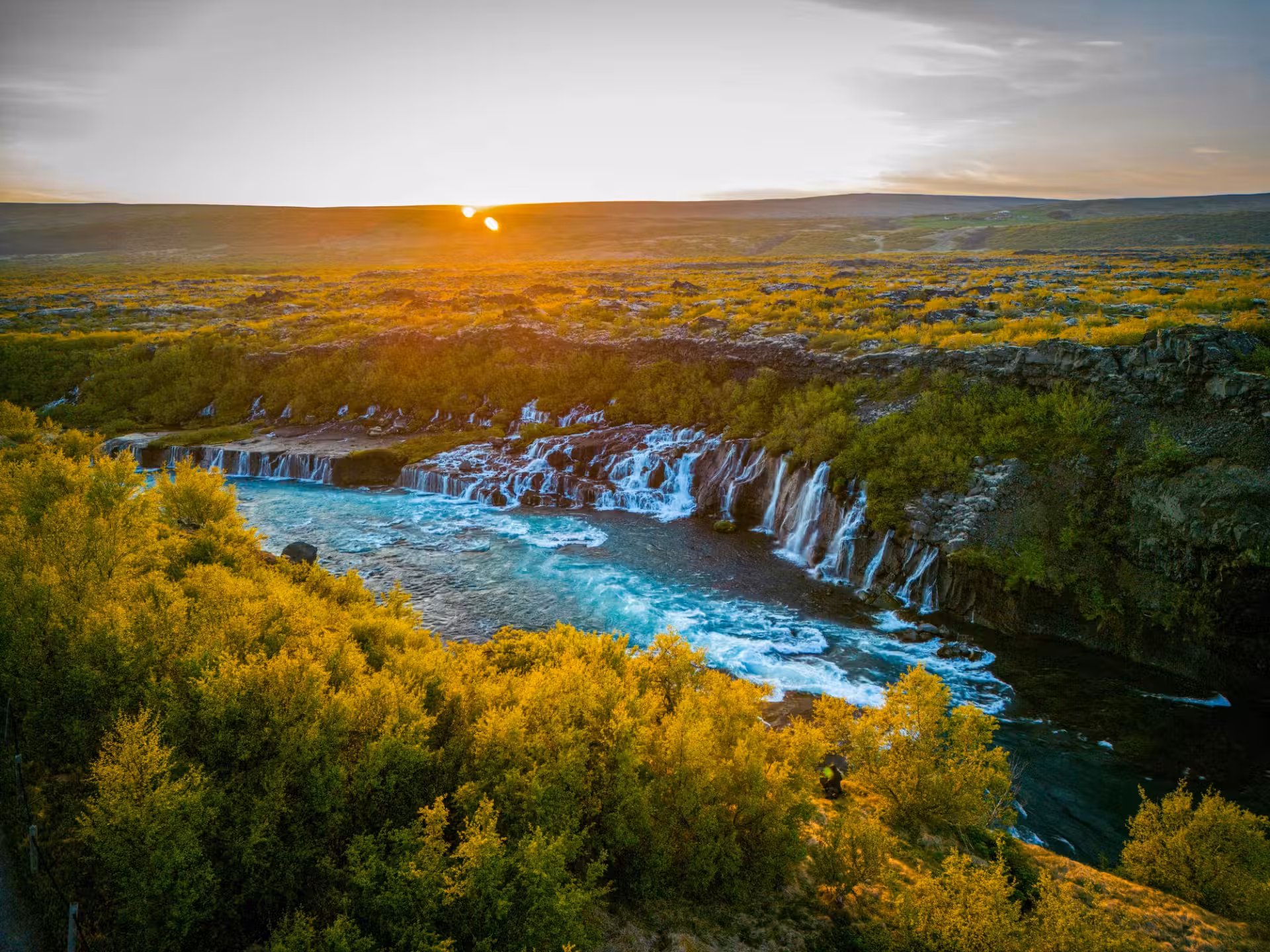 Sunset over Hraunfossar waterfalls and blue river on Silver Circle Fjord & Fire private tour Iceland