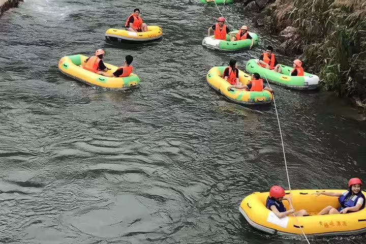 Visitors in life vests rafting through the tranquil waters of Huangteng Canyon, highlighting an adventurous day tour.
