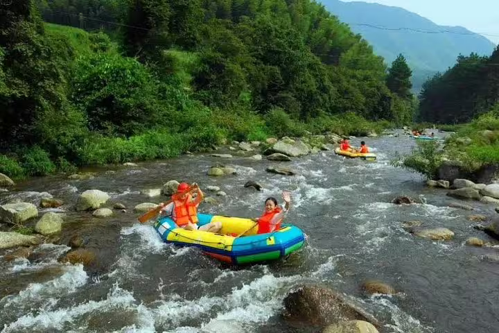 Tourists in vibrant inflatable rafts navigating the gentle rapids of Huangteng Canyon on a day tour from Guangzhou.
