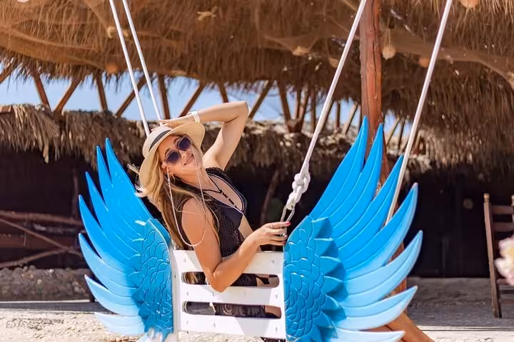Traveler relaxing on the iconic blue wing swing at Hula Hula Island Hurghada, Red Sea full-day sea trip