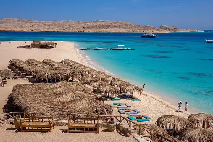 Thatched beach huts and crystal Red Sea shoreline at Hula Hula Island on VIP snorkeling day trip Hurghada