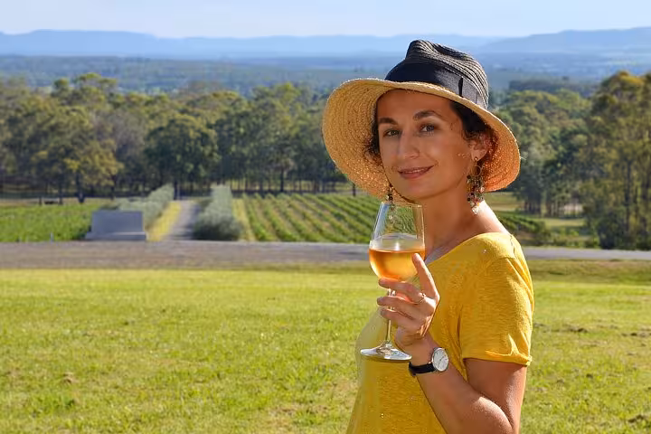 Woman enjoying a glass of wine overlooking scenic vineyards at Hunter Valley Winery, perfect for private tasting tours.