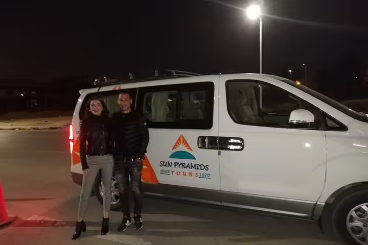 Couple beside private minivan for Hurghada Airport transfer, reliable door-to-door hotel pickup at night