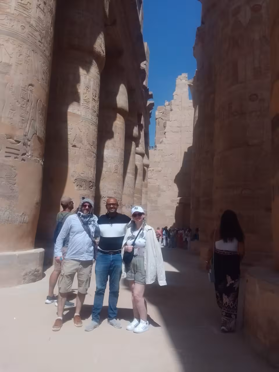 Travelers with guide at Luxor temple columns, comfortable Hurghada airport transfer for day trips and hotel drop-off