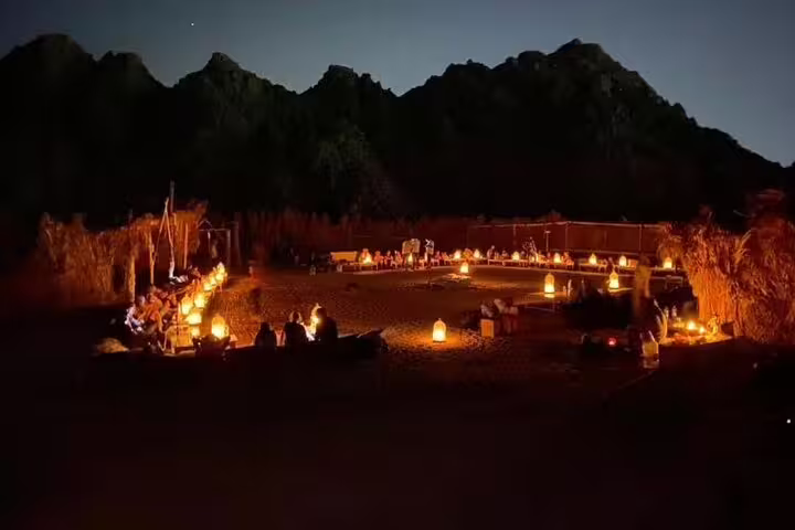 Lantern-lit Bedouin camp dinner under desert mountains on Hurghada ATV quad bike and camel safari with night show
