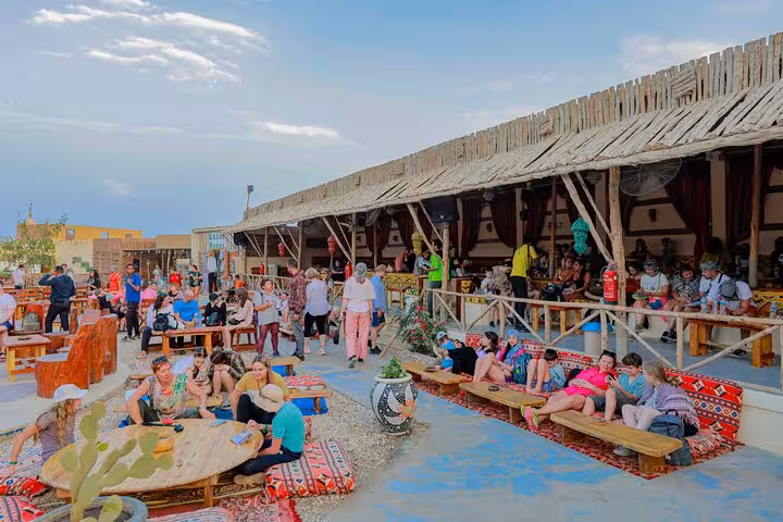 Hurghada Bedouin camp dinner setup with guests relaxing on cushions, included in desert safari show and shopping tour