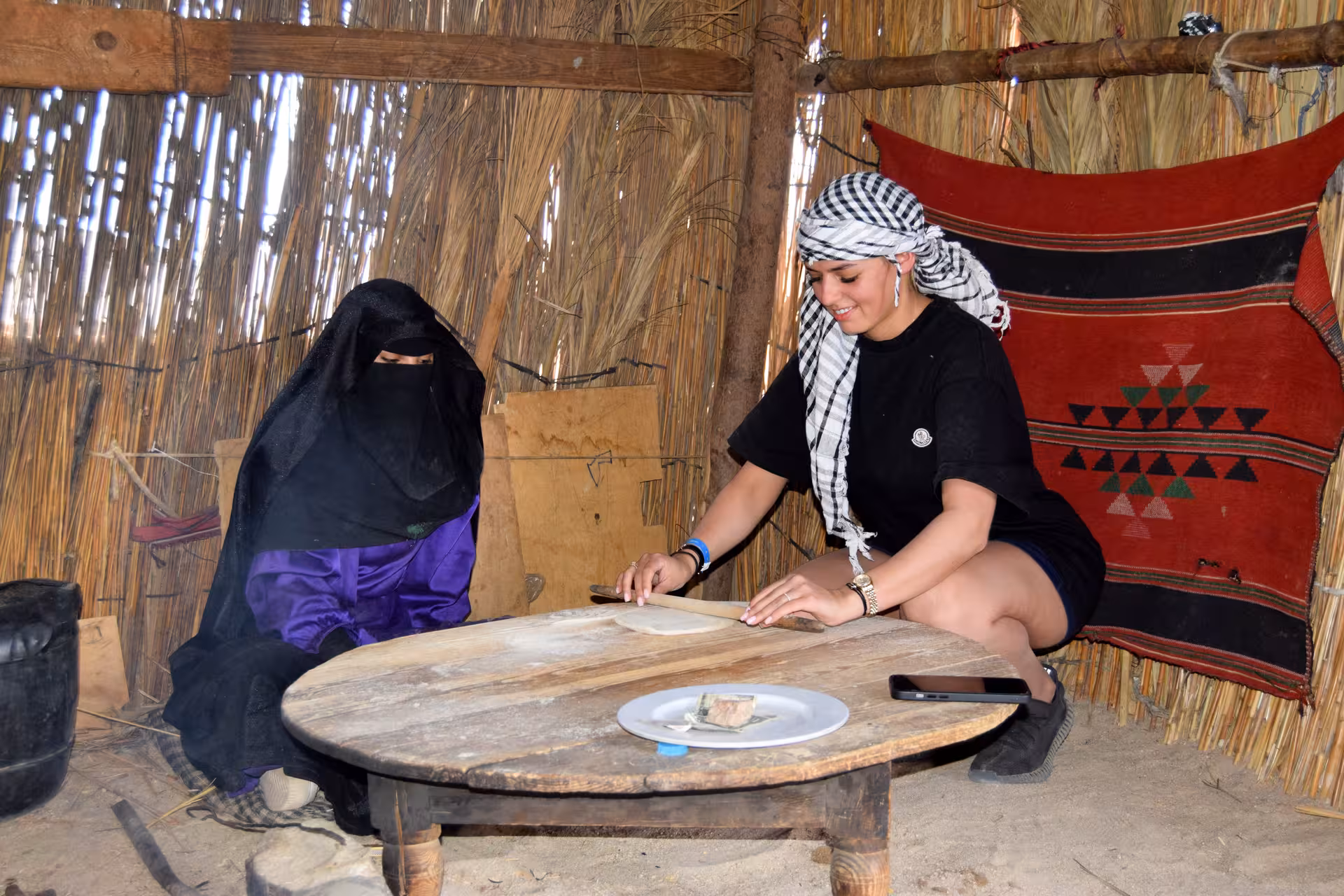 Tourist making flatbread with Bedouin host inside desert hut on Hurghada Bedouin village tour