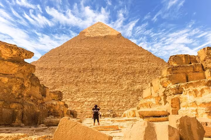 Traveler facing the Great Pyramid of Giza under blue sky on Hurghada to Cairo day trip pyramids tour