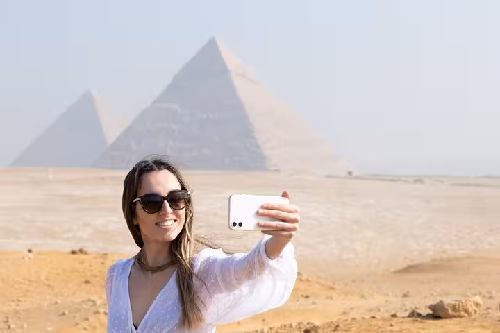 Tourist taking a selfie with the Giza Pyramids on a Hurghada to Cairo excursion, pyramids and Grand Museum visit