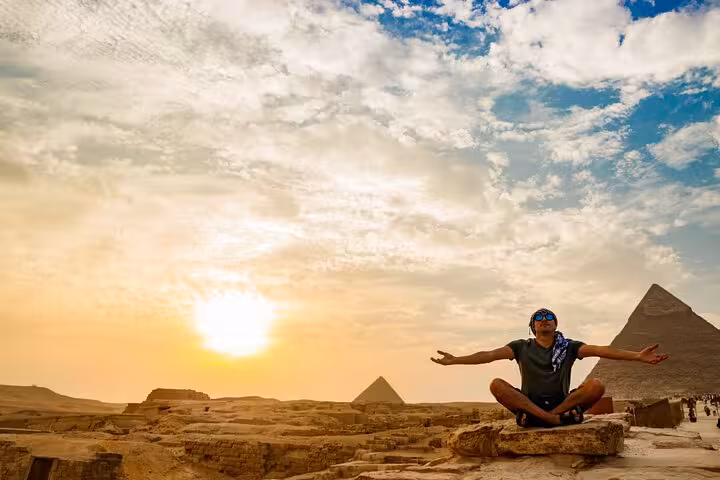 Traveler at sunset with Giza Pyramids backdrop, Cairo pyramids and Sphinx tour from Hurghada