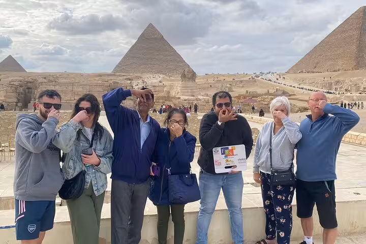 Tour group posing at Giza Plateau with Great Pyramids backdrop on Hurghada to Cairo pyramids and museum excursion