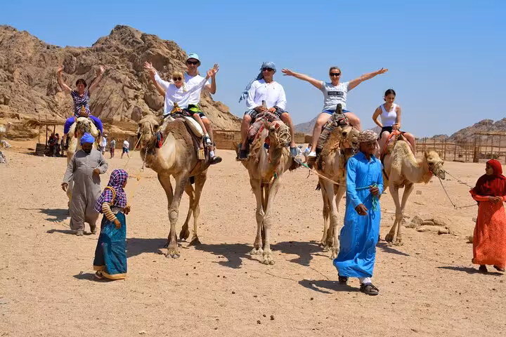 Tourists on camel ride in Hurghada desert safari, part of ATV and buggy adventure with dinner show