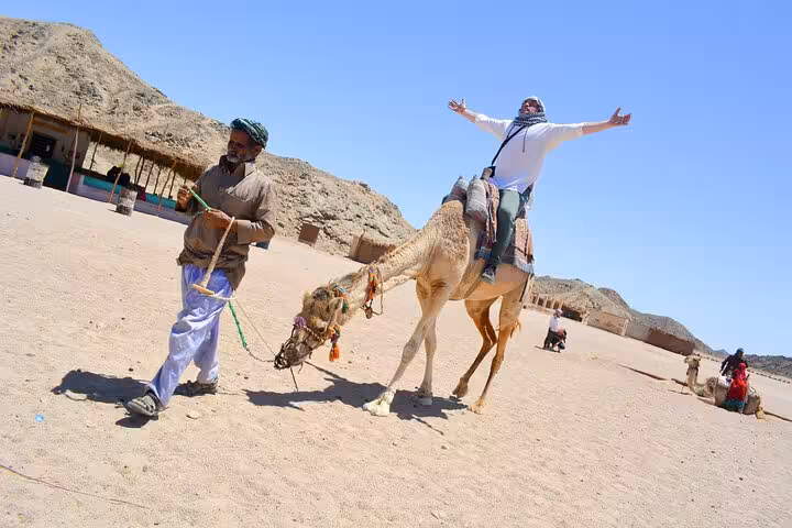Traveler enjoying camel ride in Hurghada desert camp during 3-hour safari with quad biking and shopping stop