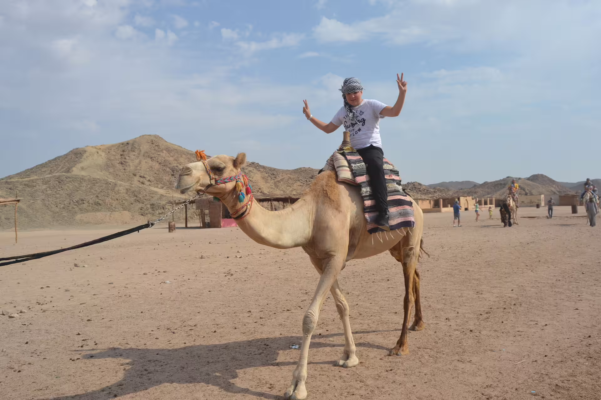 Tourist riding a camel in Hurghada desert on Mega Safari tour, enjoying scenic mountains and Bedouin camp