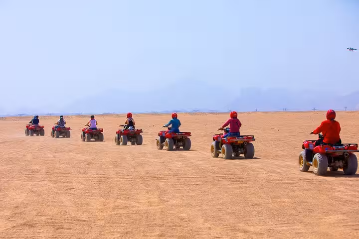 Group quad biking across Hurghada desert on Red Sea safari tour with ATV ride, dinner and show