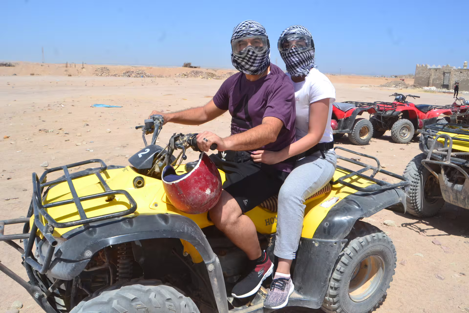 Two riders on yellow quad bike in Hurghada desert wearing scarves and goggles on Mega Safari tour