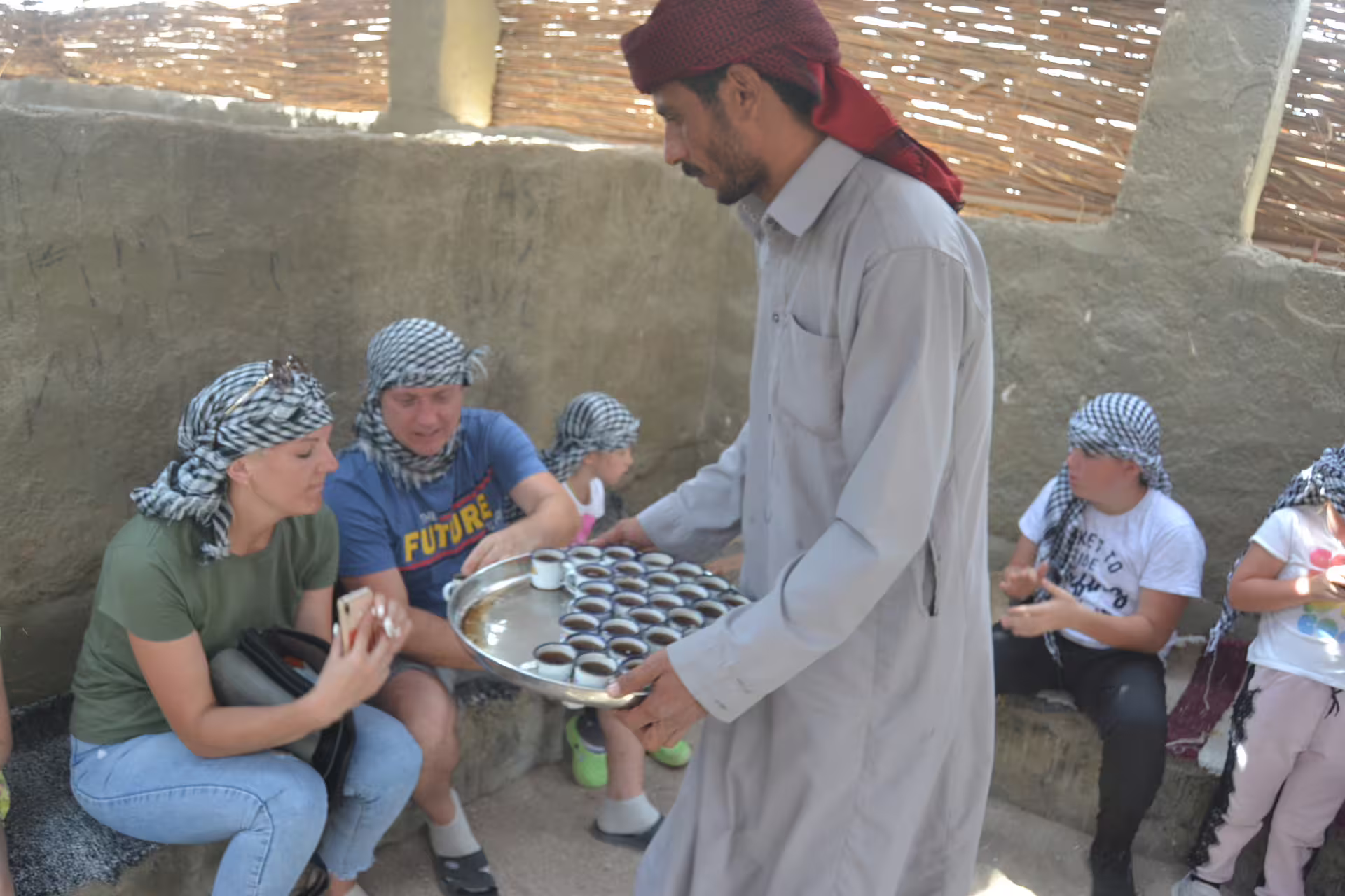 Bedouin host serving traditional tea to guests at a Hurghada desert camp on the Mega Safari adventure tour