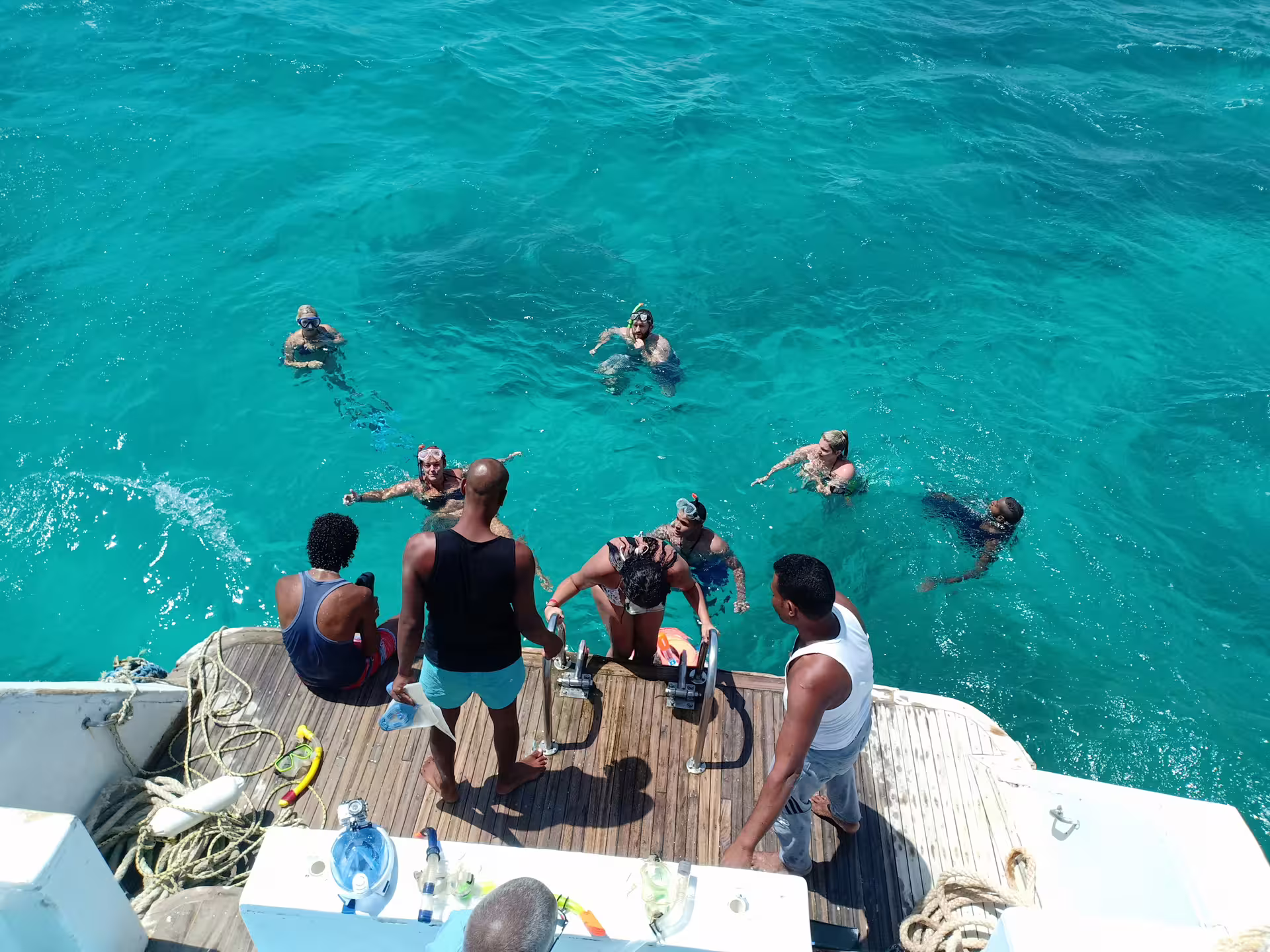 Snorkelers in crystal-clear Red Sea water boarding the boat on the Meet the Dolphins Hurghada tour