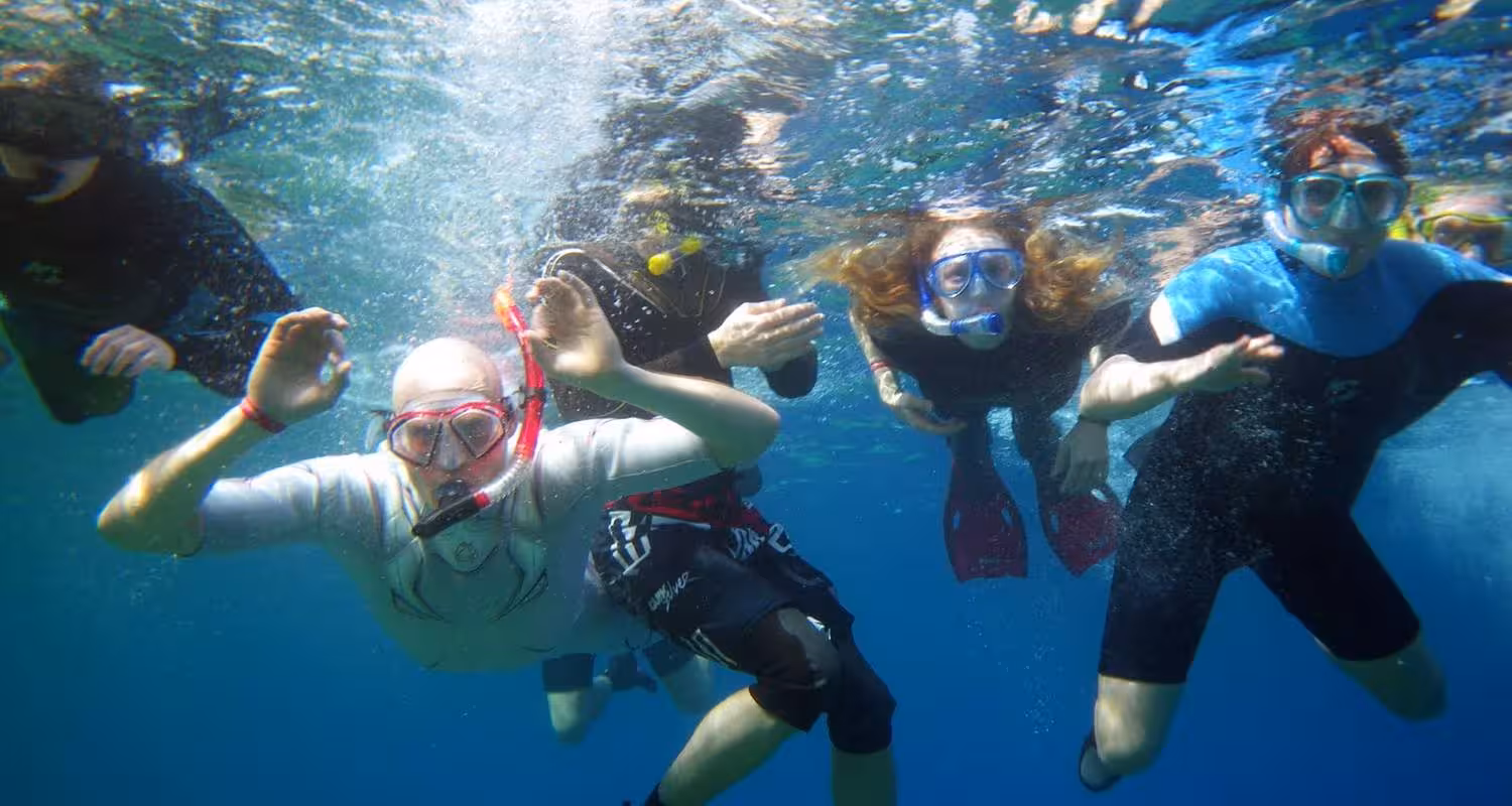 Group snorkeling in Hurghada Red Sea on Eden Island trip, clear blue water and guided reef adventure