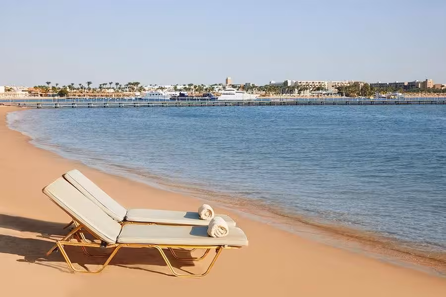 Relaxing beach scene in Hurghada with sun loungers and clear blue waters, perfect for a serene Egypt holiday.