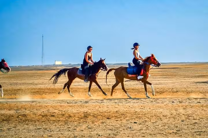 Riders galloping across Hurghada desert sands on a 2-hour horseback tour combining beach and desert views