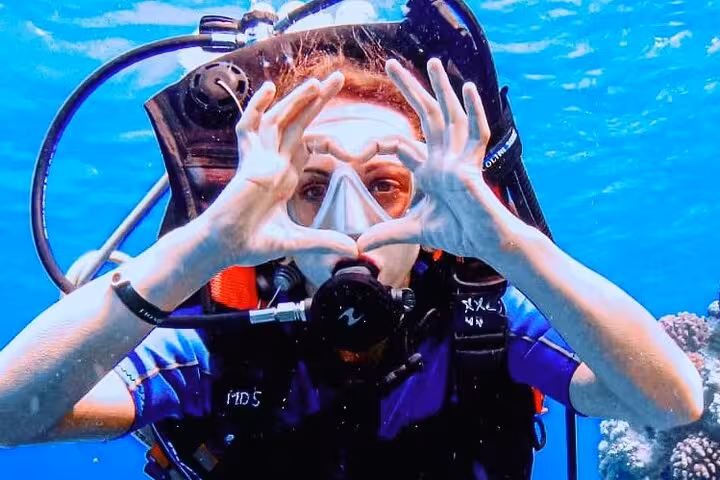 Diver making heart hands underwater on Hurghada Orange Island sea trip with Red Sea snorkeling and lunch