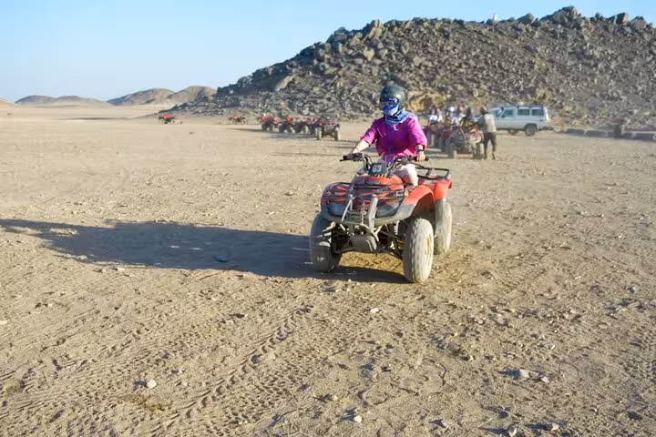 Rider on quad bike crossing Hurghada desert during 3-hour safari tour with camel ride and shopping stop