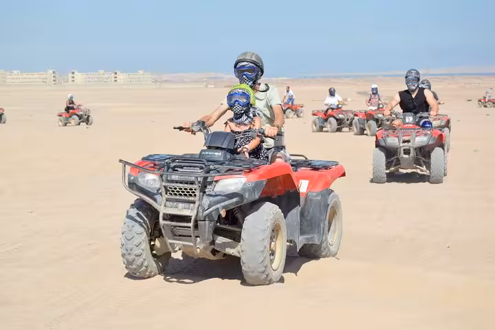 Group driving quad bikes across Hurghada desert on a 3-hour safari tour with camel ride and free shopping