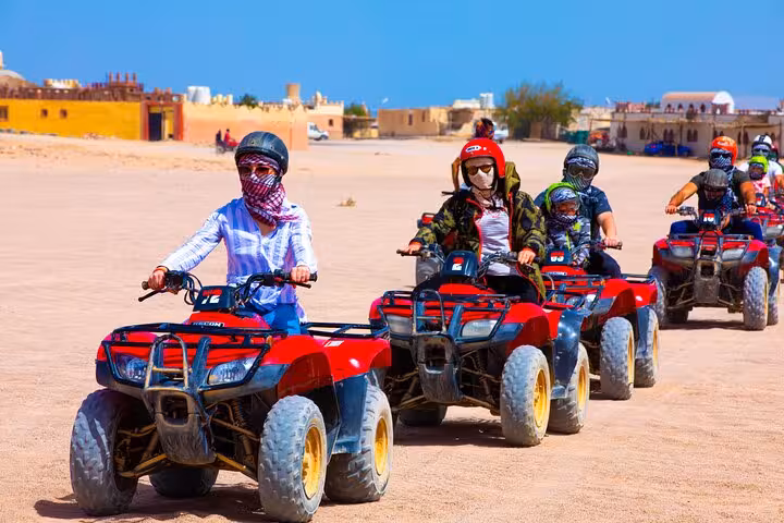 Group riding red quad bikes in Hurghada desert safari, Super Quad tour with dinner, show and shopping stop