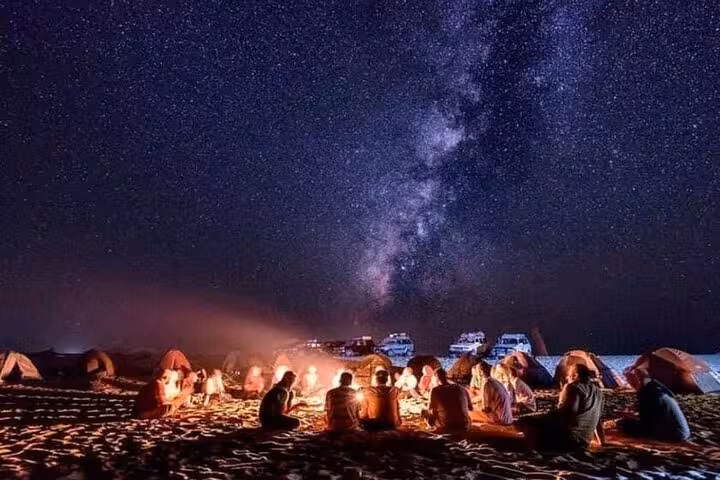 Campfire and tents under Milky Way during Hurghada desert stargazing jeep tour with optional ATV