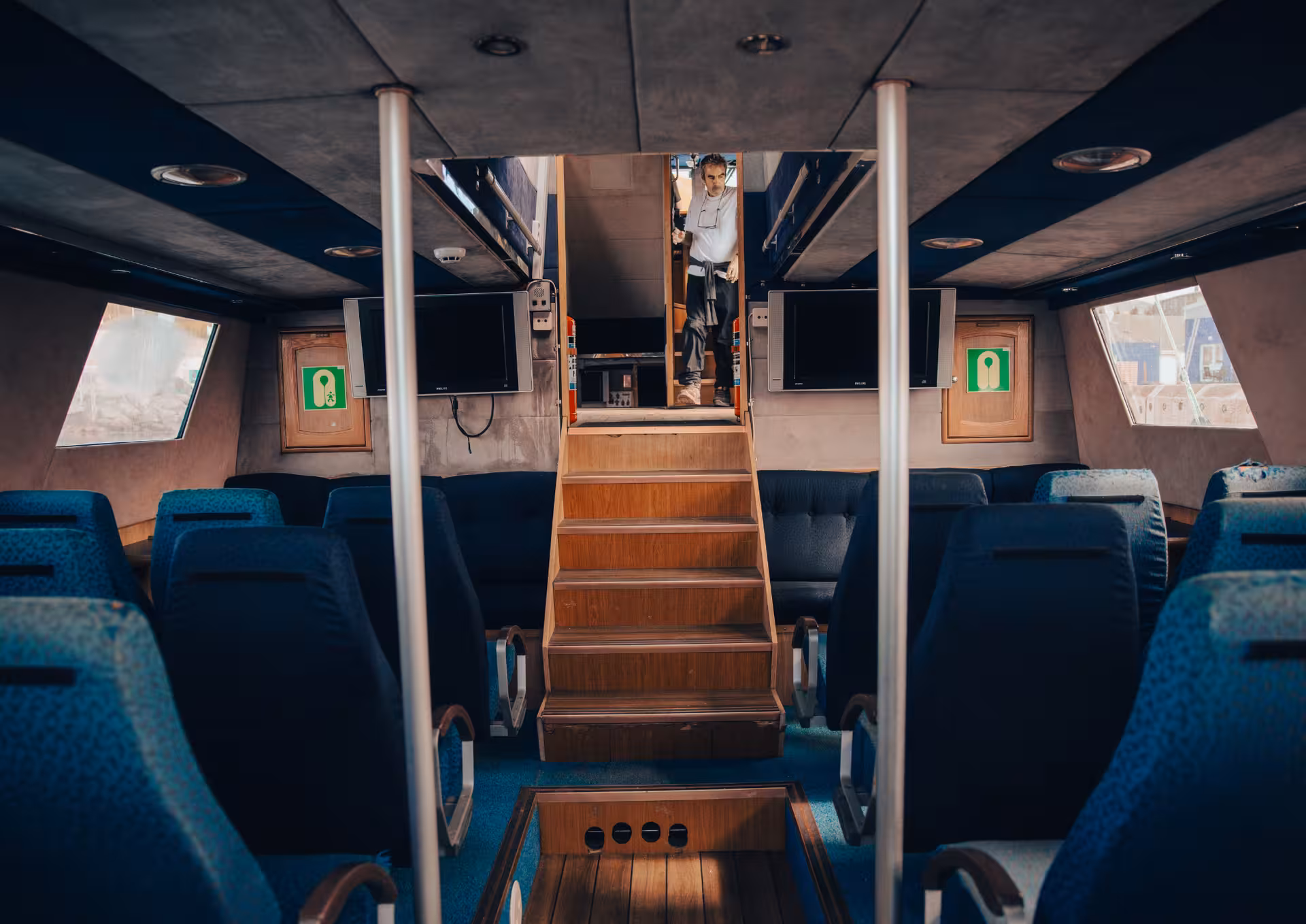 Comfortable indoor lounge on locally owned Húsavík whale watching boat, blue seats and table for families