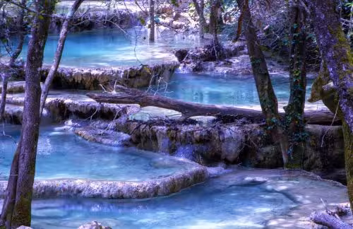 Turquoise cascades and travertine pools on the Huveaune River source hike through Provence forest
