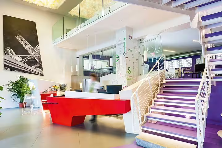 Modern ibis Styles Palermo lobby with colorful reception desk, staircase and stylish lounge for airport transfer guests