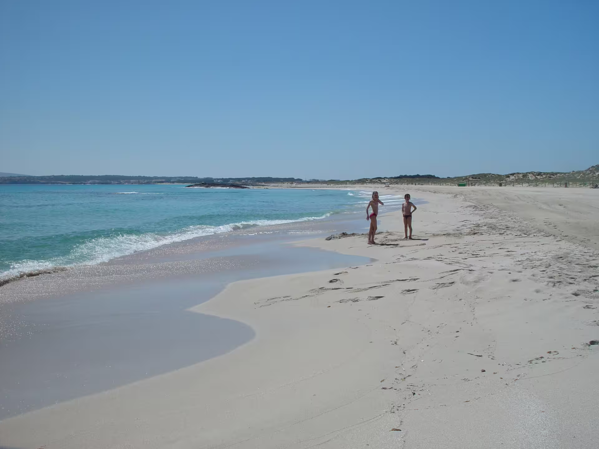 Wide sandy Ibiza beach with gentle waves, relaxing photo stop on Ibiza bus tour from Ibiza with fast ferry