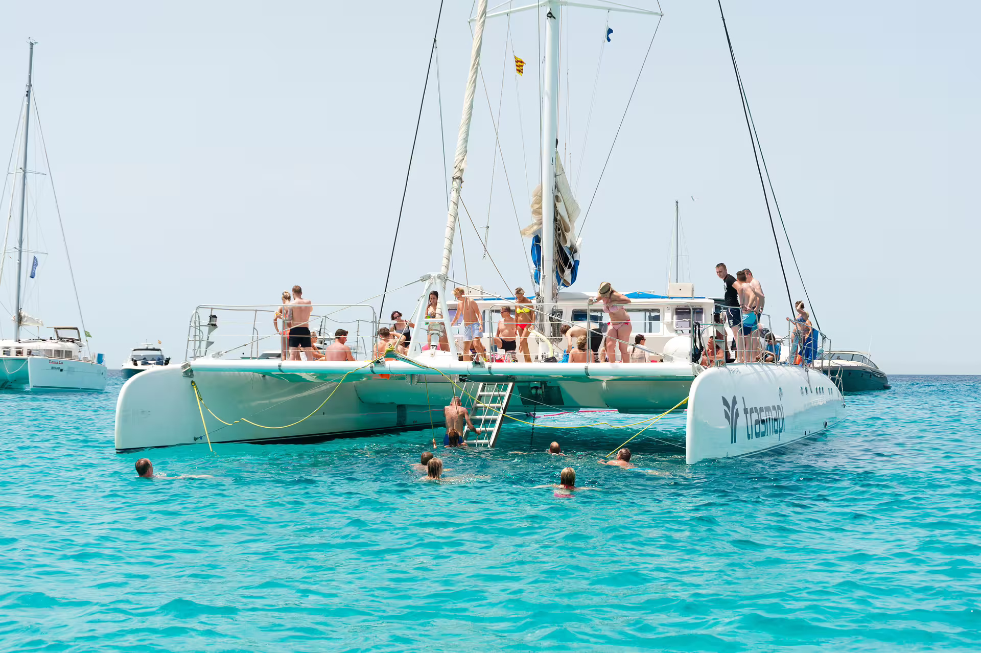 Group enjoying anchored catamaran at Illetas, Formentera day trip from Ibiza with swimming and food