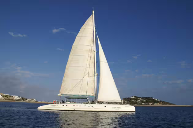 Sailing catamaran from Ibiza crossing turquoise sea toward Illetas, Formentera, on food-included day trip