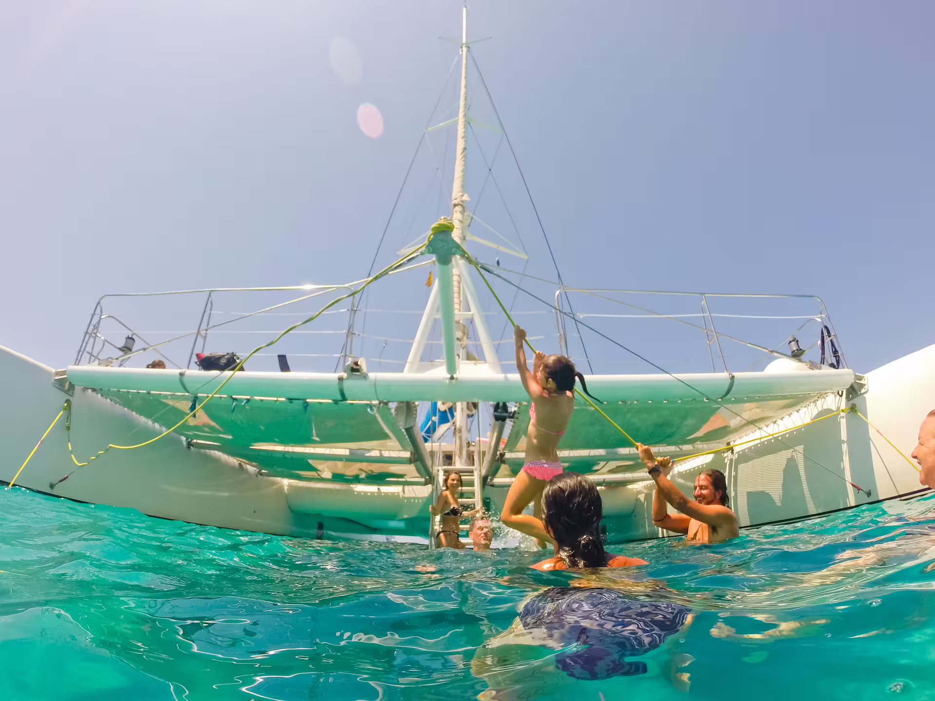 Swimmers enjoy ladder access and sea time beside catamaran at Illetas, Formentera on Ibiza cruise with lunch