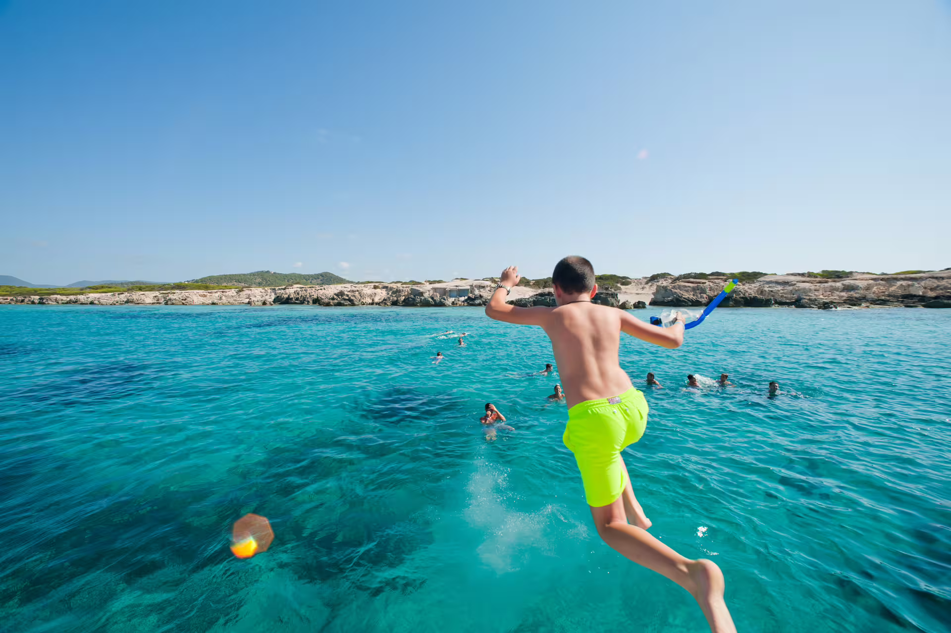 Guest jumps into turquoise Illetas waters on Ibiza to Formentera catamaran cruise with snorkel and lunch