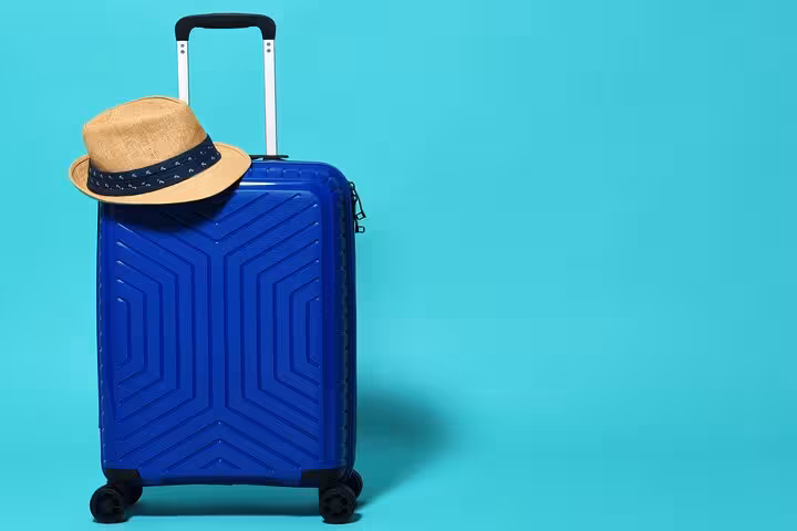 Blue carry-on suitcase with straw hat, ideal for Ibiza luggage storage near ferry port and airport